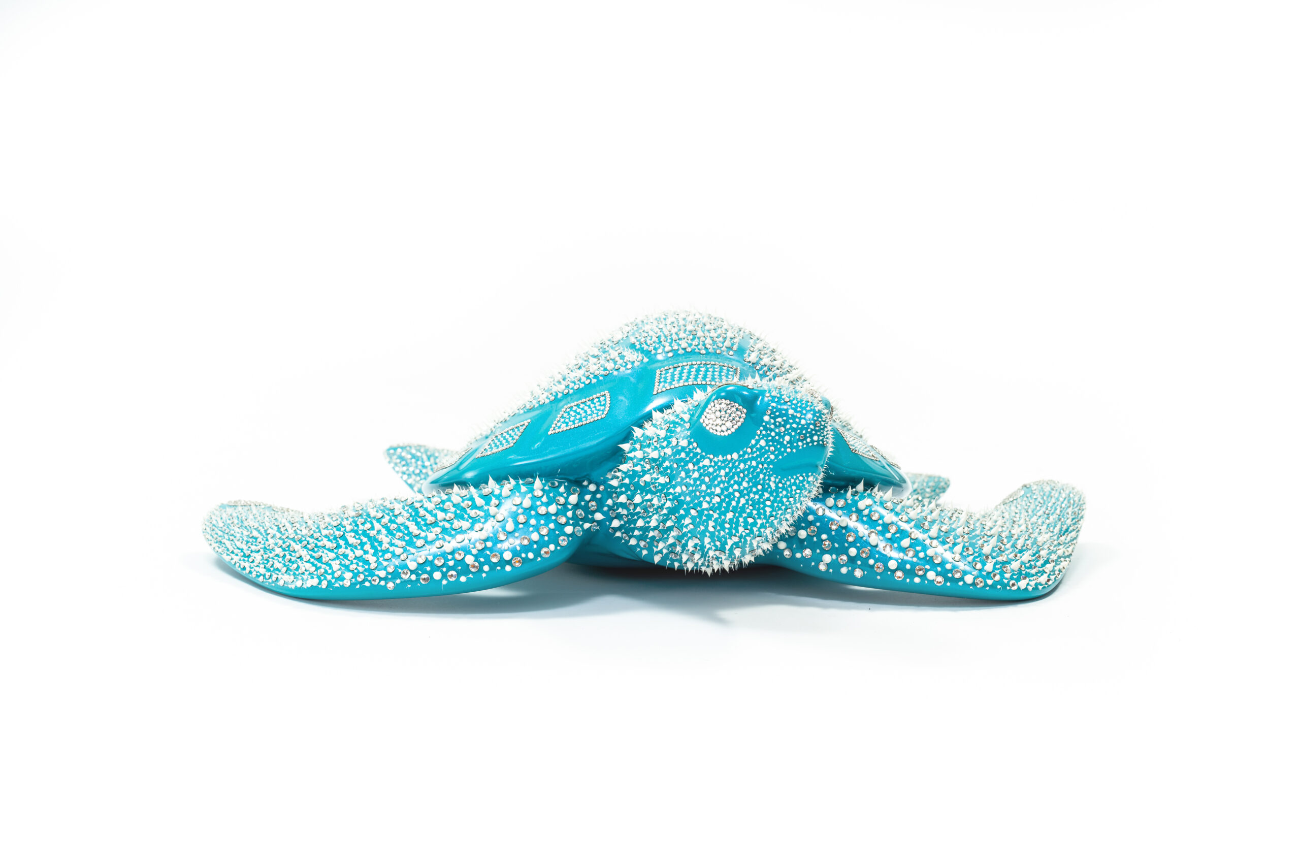 Turtle Turquoise – Eddy Maniez De Turtle Turquoise van Eddy Maniez is een meesterlijke sculptuur die onmiddellijk de aandacht grijpt. Met zijn levendige turquoise kleur en duizenden silicone dots gecombineerd met Swarovski kristallen, ademt dit werk kracht én verfijning. Het fonkelt in het licht en verandert voortdurend van uitstraling, waardoor elke blik een nieuwe ervaring biedt. Deze zeeschildpad symboliseert vrijheid, bescherming en tijdloosheid. Het werk laat zien hoe natuur en luxe elkaar kunnen versterken, zonder hun essentie te verliezen. Door de stralende turquoise tint roept Turtle Turquoise gevoelens van rust en harmonie op, terwijl de dynamische textuur juist energie en beweging uitstraalt. Dit contrast maakt de sculptuur zowel een krachtig middelpunt als een verfijnd kunstwerk dat een ruimte transformeert. Het is een kunstwerk dat niet enkel bekeken wordt, maar ook emoties losmaakt en een blijvende indruk nalaat.
