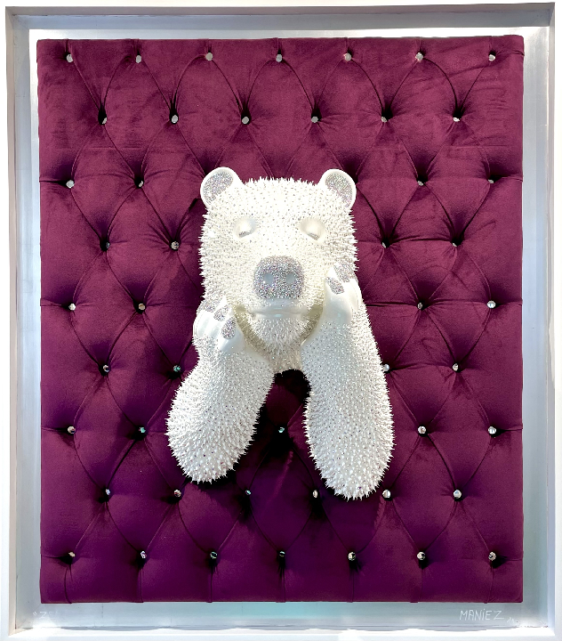 Tableau ZEN Purple – Eddy Maniez Een samensmelting van rust en luxe. Tableau ZEN Purple van Eddy Maniez trekt direct de aandacht door zijn diepe, koninklijke paarse achtergrond en de serene ijsbeer die zich door het zachte, gecapitonneerde oppervlak naar buiten laat zien. De glanzende afwerking, verrijkt met duizenden zorgvuldig aangebrachte silicone dots en Swarovski kristallen, creëert een hypnotiserend spel van licht en textuur. Dit werk ademt rust, maar straalt tegelijk onmiskenbare kracht uit. Het contrast tussen de zachtheid van het fluweel en de glinsterende details van de beer maakt dit kunstwerk uitzonderlijk intrigerend. Het tableau roept emoties op die balanceren tussen ontspanning en bewondering. Het geeft een gevoel van kalmte, terwijl de glanzende patronen voortdurend de aandacht blijven trekken. Daarom is dit kunstwerk niet alleen een lust voor het oog, maar ook een symbool van innerlijke balans en visuele harmonie. Wie dit werk in zijn ruimte plaatst, voegt onmiddellijk een iconische eyecatcher toe die gesprekken opent en tegelijkertijd een sfeer van rust bewaart.