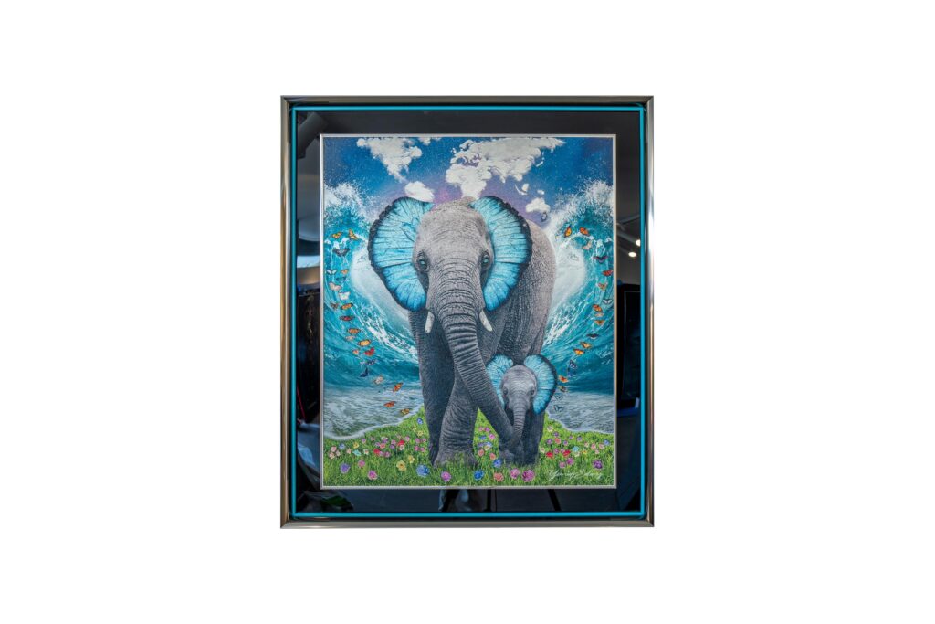 Yaniv Edery – Blue Elephant Blue Elephant van Yaniv Edery toont een majestueuze olifant die symbool staat voor kracht, wijsheid en bescherming. Met felblauwe oren, die bijna lichtgevend lijken, wordt het dier neergezet als een mythische verschijning. Achter de olifant golft het water krachtig omhoog, wat het gevoel van dynamiek en energie versterkt. Het tafereel is zowel indrukwekkend als poëtisch. De aanwezigheid van een jong olifantje naast de grote olifant benadrukt verbondenheid en zorg. Dit contrast tussen macht en tederheid maakt het werk emotioneel en gelaagd. Het blauw van de oren en de oceaan geeft rust en balans, terwijl de bloemen op de voorgrond kleur en levendigheid toevoegen. Deze details zorgen ervoor dat het kunstwerk telkens opnieuw iets nieuws onthult. Edery weet met dit kunstwerk een verhaal te vertellen. Een verhaal over kracht en harmonie, over de relatie tussen mens en natuur, maar ook over de tijdloze symboliek van de olifant. Elk detail is zorgvuldig uitgewerkt: de textuur van de huid, de sprankeling van het water, de diepte van de lucht. Het maakt het werk intens, meeslepend en onvergetelijk. Plaats Blue Elephant in een woonkamer, galerie of kantoor en ervaar hoe de ruimte onmiddellijk verandert. Het is niet slechts een decoratief object, maar een krachtig symbool dat rust, bescherming en hoop uitstraalt.