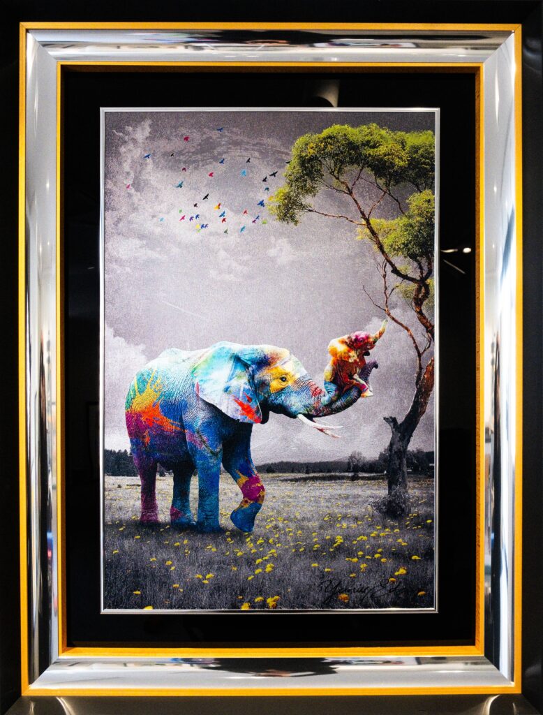 Yaniv Edery – Elephant Multicolor Dit schitterende kunstwerk van Yaniv Edery toont een olifant in een explosie van kleuren. Het dier, normaal symbool van kracht en wijsheid, krijgt hier een moderne en expressieve uitstraling. Met felle tinten rood, blauw, geel en oranje is de olifant omgetoverd tot een levendig kunstobject vol energie en vreugde. Het contrast met de grijze achtergrond benadrukt de intensiteit van de kleuren. De bloemen in het gras en de vogels in de lucht voegen extra levendigheid toe. De scène straalt harmonie en vrijheid uit, maar ook een vleugje speelsheid. Dit maakt het werk zowel poëtisch als krachtig. De compositie vertelt een verhaal van balans tussen natuur en creativiteit. De olifant speelt met een boom, wat tederheid en speelsheid symboliseert. Tegelijkertijd staat het imposante dier stevig en zelfverzekerd in het landschap. Deze combinatie van kracht en zachtheid geeft het werk een diepe gelaagdheid. Edery weet emoties op te roepen door kleur, contrast en detail. Elk vlak en elke penseelstreek dragen bij aan een dynamisch geheel. Elephant Multicolor is geen simpel beeld, maar een symbool van vreugde, vrijheid en verbondenheid. Het kunstwerk spreekt direct tot de verbeelding en blijft fascineren. Het stuk leent zich perfect als statement binnen moderne kunstcollecties en straalt universaliteit uit. Het toont hoe kunst natuur kan verheffen tot iets nog groters: een visueel verhaal vol kracht en schoonheid.