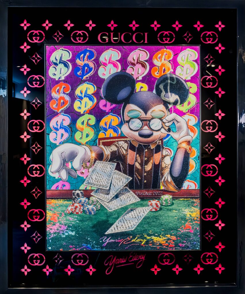 Yaniv Edery – Mickey Poker Laser Cut Dit bijzondere kunstwerk van Yaniv Edery brengt popcultuur, luxe en humor samen in één krachtig beeld. Mickey Mouse is hier afgebeeld als serieuze pokerspeler, compleet met kaarten, fiches en een zelfverzekerde blik. De combinatie van zijn iconische figuur met de wereld van luxe en gokken creëert een spannend en ironisch contrast. De achtergrond bestaat uit kleurrijke dollartekens en het kenmerkende Gucci-patroon. Dit benadrukt de luxueuze sfeer en voegt een speelse laag van ironie toe. De laser cut-techniek geeft extra diepte en glans, waardoor het kunstwerk een moderne en hoogwaardige uitstraling krijgt. Edery gebruikt felle kleuren en scherpe details om spanning en energie in het werk te brengen. Mickey, normaal symbool van vrolijkheid en jeugdcultuur, wordt hier neergezet als een serieuze speler in de wereld van status en macht. Dit contrast maakt het werk verrassend en gelaagd. De sigaar in zijn mond en de stapels geld versterken het thema van luxe en bravoure. Tegelijkertijd zorgt de humoristische toon voor luchtigheid. Het werk daagt uit om na te denken over consumptie, geluk en de waarde die we hechten aan iconen. Mickey Poker Laser Cut is daardoor niet enkel decoratief, maar ook een krachtig statement. Het kunstwerk weet steeds opnieuw te boeien. De combinatie van luxe, popcultuur en speelsheid maakt het tot een opvallend stuk dat energie uitstraalt en nieuwsgierigheid wekt.
