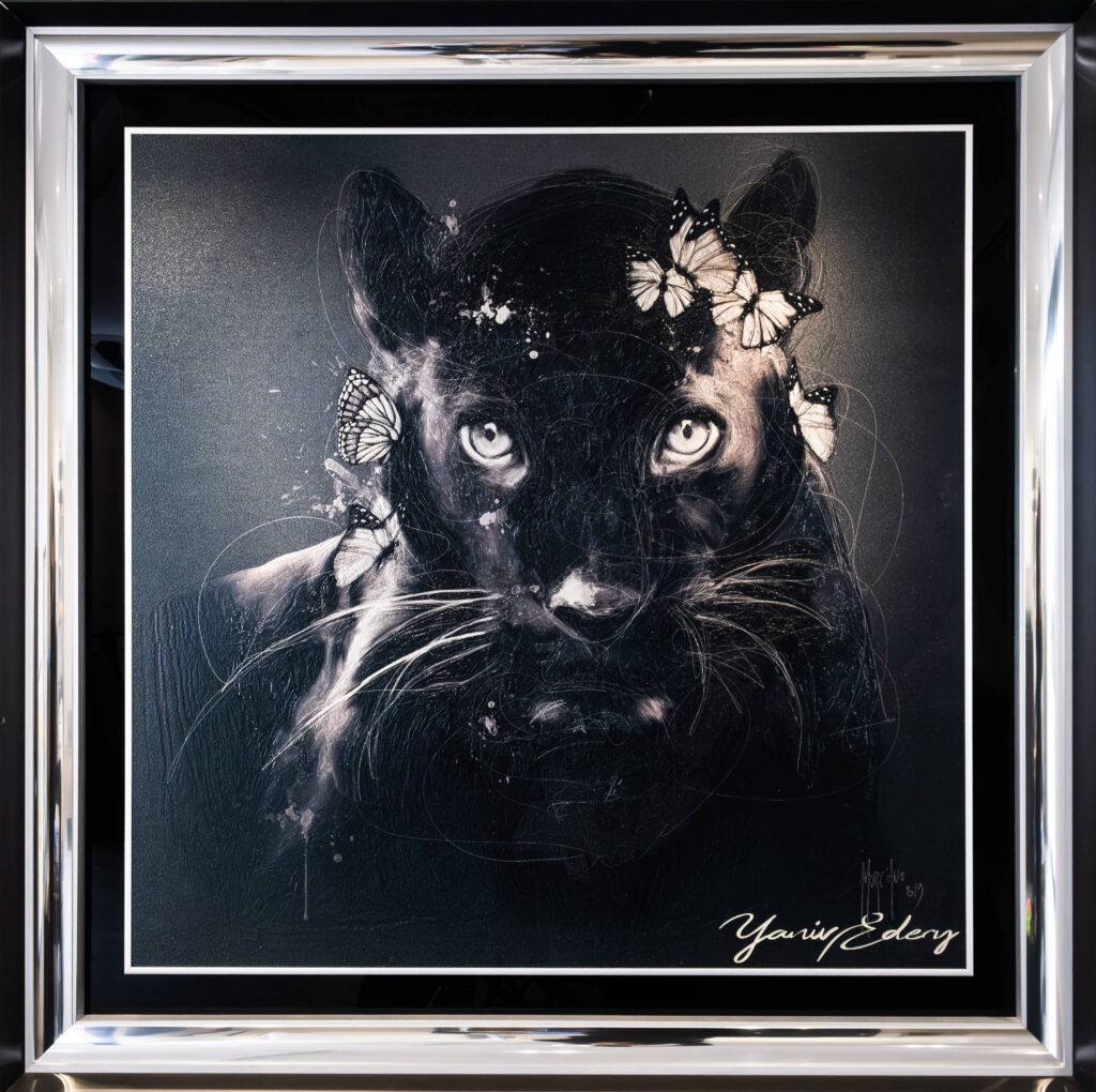 Yaniv Edery, Black Panter Butterfly Yaniv Edery – Black Panter Butterfly is een krachtig kunstwerk dat elegantie en mysterie samenbrengt. De zwarte panter staat centraal. Zijn doordringende ogen trekken direct de aandacht. Het gebruik van contrast tussen donker en licht zorgt voor spanning en intensiteit. Vlinders omringen de panter subtiel. Zij voegen een onverwachte zachtheid en verfijning toe. Dit contrast tussen kracht en kwetsbaarheid maakt het werk intrigerend. De fragiele vlinders staan symbool voor vrijheid, hoop en verandering. De panter vertegenwoordigt moed, instinct en kracht. Samen vertellen ze een verhaal van balans en harmonie. Het spel met zwart-wit geeft het werk diepte en gelaagdheid. De glanzende details en lichte accenten versterken de mysterieuze uitstraling. Daardoor voelt de panter bijna levensecht aan. Elk detail draagt bij aan de intensiteit van de compositie. Edery speelt bewust met emoties. De blik van de panter is tegelijk waakzaam en betoverend. Het kunstwerk roept vragen op, prikkelt de verbeelding en nodigt uit tot interpretatie. Daarom is Black Panter Butterfly niet zomaar een portret, maar een symbool van kracht in combinatie met schoonheid. Het werk benadrukt de dualiteit van de natuur: ruw en zacht, donker en licht, sterk en breekbaar. Deze tegenstelling maakt het beeld tijdloos en universeel.