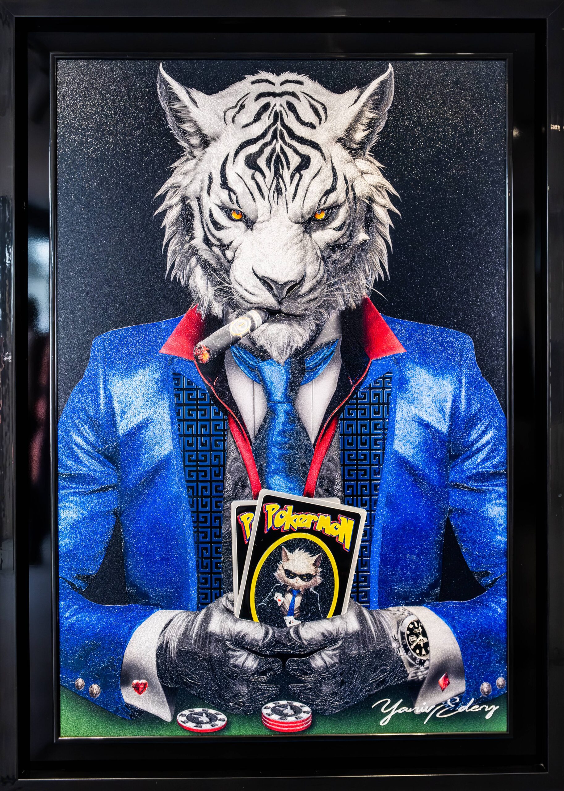 Yaniv Edery – Tiger Pok'Art Blue Suit Dit intrigerende kunstwerk van Yaniv Edery toont een trotse witte tijger, gekleed in een elegant blauw pak. Met een sigaar in de mond en kaarten in de hand straalt hij macht, lef en zelfvertrouwen uit. De intense gele ogen grijpen direct de aandacht en geven het werk een krachtige, bijna intimiderende uitstraling. De speelse twist zit in de kaarten die hij vasthoudt: opvallende Pokémon-kaarten. Dit onverwachte element doorbreekt de serieuze sfeer en zorgt voor humor en gelaagdheid. Het werk combineert luxe en elegantie met jeugdcultuur en speelsheid. Daardoor ontstaat een verrassend contrast dat de kijker blijft boeien. De compositie is sterk en zorgvuldig opgebouwd. Het glanzende blauwe pak, de rode accenten en de strakke details benadrukken stijl en klasse. Tegelijkertijd verwijzen de kaarten en de sigaar naar thema’s als macht, strategie en spel. Dit maakt het kunstwerk meer dan decoratief: het is een symbool van lef, luxe en ironie. Edery laat hier zijn talent zien voor het spelen met tegenstellingen. De kracht van de tijger, gecombineerd met de onverwachte speelsheid van popcultuur, maakt dit werk uniek. Het vertelt een verhaal over status, identiteit en de rol van symbolen in onze cultuur. Elk detail, van de textuur van de vacht tot de patronen in het kostuum, is uitgewerkt met precisie. Tiger Pok’Art Blue Suit is een statement piece dat energie en stijl uitstraalt en tegelijk een glimlach weet op te roepen.