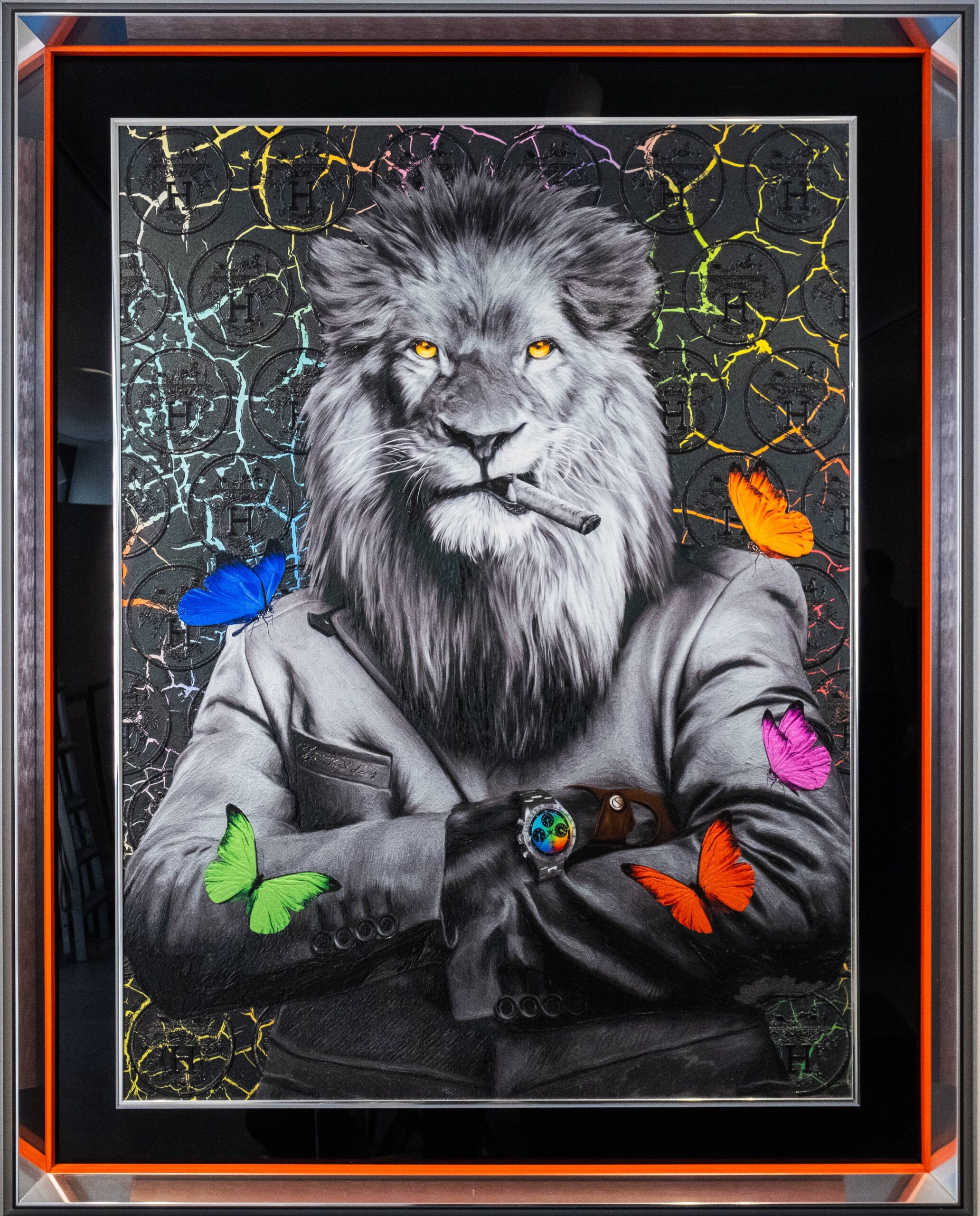 Yaniv Edery – Lion Multicolor Butterfly Dit indrukwekkende kunstwerk van Yaniv Edery toont een trotse leeuw die kracht en zelfvertrouwen uitstraalt. De leeuw, gehuld in een strak zwart pak en met een sigaar tussen zijn tanden, kijkt de toeschouwer met een intense blik aan. Zijn gouden ogen vangen direct de aandacht en benadrukken zijn majesteitelijke aanwezigheid. Wat dit werk bijzonder maakt, zijn de kleurrijke vlinders die rond de leeuw dansen. Felblauwe, groene, oranje, roze en paarse accenten contrasteren met het monochrome zwart-wit van de leeuw zelf. Deze speelse toevoeging verzacht het krachtige beeld en brengt balans tussen dominantie en lichtheid. Het resultaat is een harmonieus en verrassend geheel. Edery speelt met tegenstellingen: macht tegenover kwetsbaarheid, ernst tegenover speelsheid. De vlinders, vaak symbool voor transformatie en vrijheid, voegen een poëtische laag toe aan het werk. Ze brengen lucht en beweging in de compositie, terwijl de leeuw onverstoorbaar en vastberaden blijft. Dit contrast geeft het kunstwerk diepte en maakt het gelaagd. De achtergrond, met zijn gebarsten textuur en subtiele glans, versterkt de dramatische sfeer. Elk detail, van de haren in de manen tot de glans van het horloge om zijn pols, is zorgvuldig uitgewerkt. Lion Multicolor Butterfly is niet enkel een visueel spektakel, maar ook een krachtig symbool voor balans, luxe en persoonlijke kracht. Dit kunstwerk weet zowel te imponeren als te inspireren. Het vangt de essentie van kracht en verfijning, maar voegt er tegelijkertijd een speelse twist aan toe die steeds opnieuw verrast.
