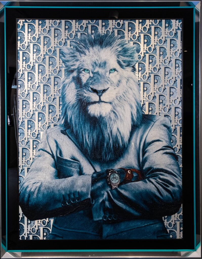 Yaniv Edery – Lion Dior Kracht en luxe ontmoeten elkaar in dit opvallende kunstwerk van Yaniv Edery. De leeuw, symbool van macht en trots, wordt hier gekleed in een modern Dior-pak. Het ontwerp straalt autoriteit en zelfvertrouwen uit. De strak gevouwen armen benadrukken vastberadenheid en controle. De achtergrond met het iconische Dior-patroon versterkt de link met high fashion en exclusiviteit. De blauwe tinten geven het werk een frisse en koele uitstraling. Bovendien zorgt het subtiele gebruik van reliëf en details voor een krachtige visuele impact. De horloge om de pols van de leeuw benadrukt niet alleen stijl, maar ook status en tijdloze klasse. Signaalwoorden zoals luxe, kracht, exclusief en opvallend maken duidelijk wat dit kunstwerk bijzonder maakt. De combinatie van klassieke symboliek en moderne mode zorgt voor spanning en balans. De trotse blik van de leeuw, samen met het high-end mode-element, maakt dit werk tot een ultiem statement piece. Dit werk is niet zomaar een kunstwerk. Het is een moderne interpretatie van kracht in de taal van de hedendaagse kunst. Yaniv Edery combineert in Lion Dior zijn unieke gevoel voor detail met een verrassende mix van cultuur, mode en symboliek.
