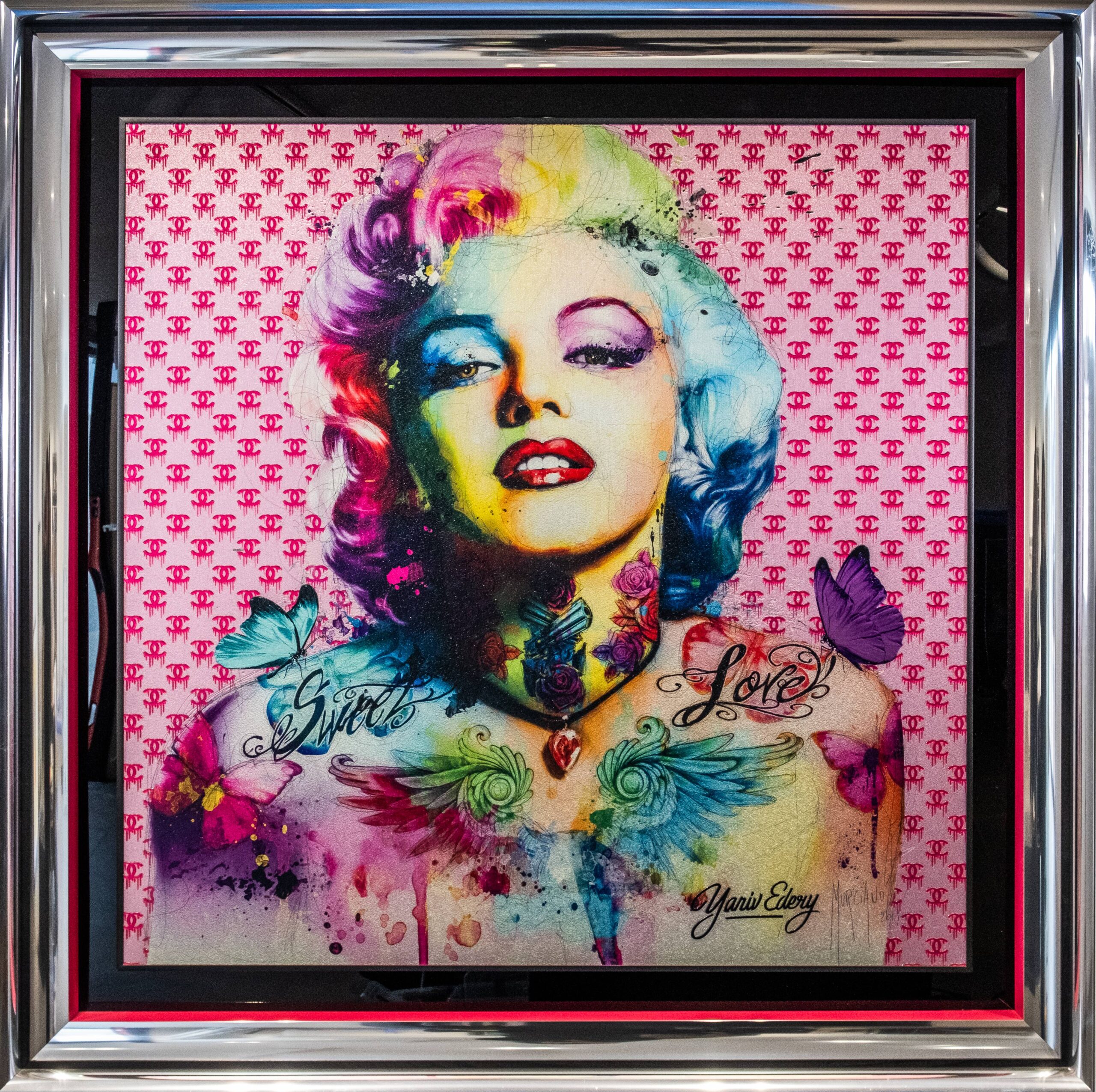 Yaniv Edery, Marilyn Pink Butterfly Yaniv Edery – Marilyn Pink Butterfly is een ode aan glamour en iconische schoonheid. Het werk toont Marilyn Monroe in een moderne, kleurrijke interpretatie. Haar klassieke uitstraling wordt verrijkt met een explosie van tinten die het portret energie en diepte geven. De felroze achtergrond, gecombineerd met subtiele patronen, versterkt haar charisma. Opvallend zijn de vlinders die rondom haar verschijnen. Zij symboliseren vrijheid, transformatie en lichtheid. Samen met de tattoos op haar borst – Love en Girl – ontstaat een krachtig contrast tussen zachtheid en rebellie. Daardoor krijgt dit portret een eigentijdse, bijna provocerende uitstraling. Edery kiest bewust voor sterke kleurcontrasten. De mix van pastel en neon geeft het werk een levendig en speels karakter. Het is kunst die direct aanspreekt, herkenning oproept én verrast. De blik van Marilyn is verleidelijk en uitdagend. Haar pose straalt zelfverzekerdheid en allure uit. Bovendien verwijst dit werk naar thema’s als idoolcultuur, vrouwelijkheid en de verleidelijke kracht van iconen. Monroe wordt hier niet alleen als ster, maar ook als symbool van vrijheid en verandering neergezet. Dit maakt het werk tijdloos en relevant. Het gebruik van vlinders geeft een extra dimensie. Zij brengen beweging en luchtigheid in het beeld. Daardoor voelt het portret zowel klassiek als dynamisch. Edery weet met Marilyn Pink Butterfly een perfecte balans te vinden tussen nostalgie en hedendaagse kunst.