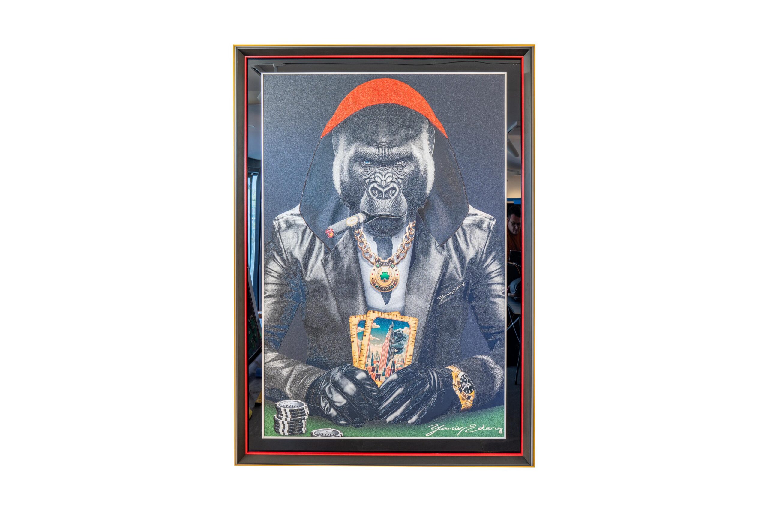 Yaniv Edery – Gorilla Poker Cape Red is een krachtig kunstwerk dat dominantie, luxe en stijl samenbrengt. De imposante gorilla zit aan de pokertafel, gehuld in een stoere leren jas en een felrode cape. De details trekken meteen de aandacht: een grote gouden ketting, opvallende ringen en een sigaar die kracht en autoriteit symboliseert. De rode cape is niet alleen een stijlvol detail, maar ook een symbool van macht en leiderschap. Het maakt de gorilla tot een ware heerser van het spel. Daarbij versterken de felle contrasten en diepe kleuren de intensiteit van het werk. De blik van de gorilla is vastberaden en onverzettelijk. Hij straalt uit dat hij controle heeft over de kaarten en daarmee over de hele situatie. Het poker-thema geeft het kunstwerk een extra laag. Poker draait om risico, strategie en durf. Precies deze elementen weet Edery te vertalen naar zijn kunst. De kaarten, de fiches en de houding van de gorilla brengen spanning en elegantie samen. Het werk voelt tegelijk speels én indrukwekkend, een combinatie die blijft fascineren. Elk detail in dit werk is zorgvuldig gekozen. Van de glans op de sieraden tot de scherpe contouren van de gorilla’s gezicht, alles ademt luxe en kracht. Dit maakt het kunstwerk niet alleen een visueel hoogtepunt, maar ook een verhaal over macht, lef en identiteit. Gorilla Poker Cape Red is een blikvanger die een ruimte volledig transformeert. Het straalt energie, zelfvertrouwen en karakter uit, en nodigt uit tot gesprek en bewondering.