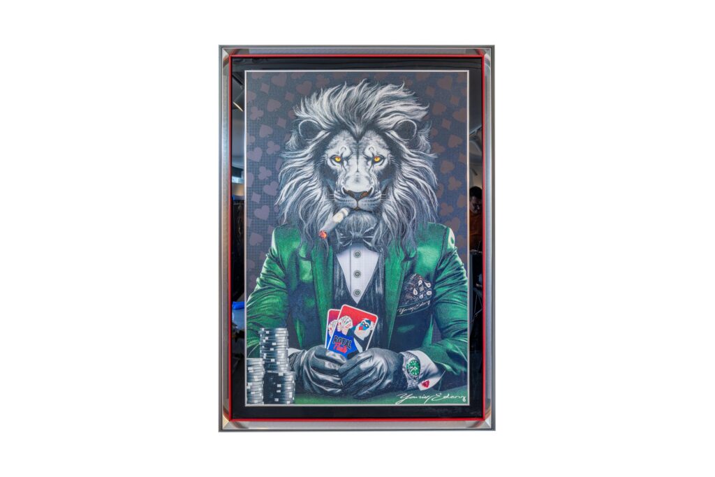 Yaniv Edery – Lion Poker Green Suit Dit kunstwerk ademt kracht, luxe en mysterie. Een trotse leeuw, de koning van de dieren, zit zelfverzekerd aan de pokertafel. Gekleed in een stijlvol groen pak, straalt hij macht en elegantie uit. De ogen zijn scherp, de houding onwankelbaar. De kaart in zijn hand symboliseert strategie en dominantie. Het groene kostuum geeft het werk een energieke uitstraling. Groen staat voor balans, groei en succes. De zwarte strik en het witte hemd brengen verfijning en contrast. Tegelijk benadrukt de achtergrond met hartpatronen de intensiteit van het pokerspel. Elk detail is zorgvuldig uitgewerkt, van de rook van de sigaar tot de glans op de fiches. Dit werk is niet alleen decoratief, maar ook betekenisvol. Het toont hoe instinct en intelligentie samenkomen in spel en in leven. De leeuw is een symbool van moed en leiderschap. In dit kunstwerk wordt hij gepresenteerd als speler en winnaar, maar ook als icoon van stijl. Lion Poker Green Suit is daarmee een perfecte combinatie van kunst, kracht en luxe. Het is een statement piece dat direct de aandacht trekt en elke ruimte karakter geeft.