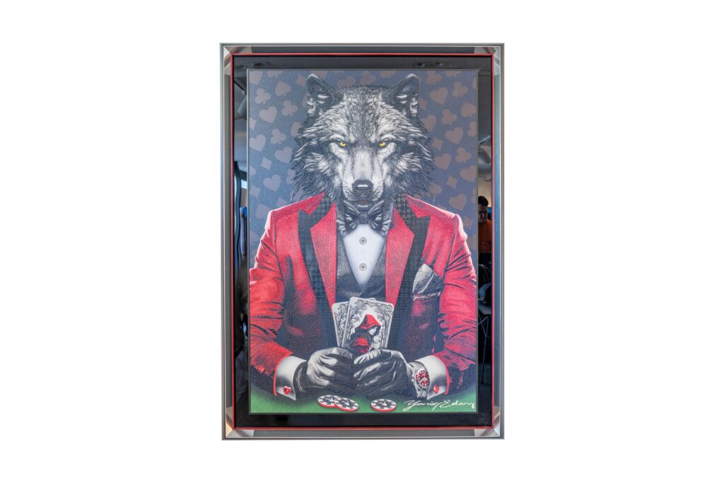 Yaniv Edery – Wolf Poker Red Suit Dit kunstwerk straalt kracht en elegantie uit. Een wolf in een stijlvol rood pak, zittend aan de pokertafel. Het dier houdt de kaarten stevig vast en kijkt zelfverzekerd vooruit. Het rode kostuum symboliseert lef en dominantie. Tegelijkertijd geeft het zwarte hemd met strikje een vleugje verfijning en klasse. De achtergrond toont subtiele hartpatronen, die de spanning van het spel benadrukken. Het contrast tussen de donkere wolvenkop en het felle rood maakt het werk intens en meeslepend. Elk detail – van de fijne lijnen in de vacht tot de perfect afgebeelde fiches – draagt bij aan een beeld dat direct indruk maakt. Dit kunstwerk laat zien hoe instinct, stijl en macht samenkomen. Het is meer dan een decoratief stuk: het vertelt een verhaal. Over strategie, risico’s en de kracht om te winnen. Daarmee is Wolf Poker Red Suit ideaal voor wie een sterk en sprekend kunstwerk zoekt dat klasse en karakter combineert.