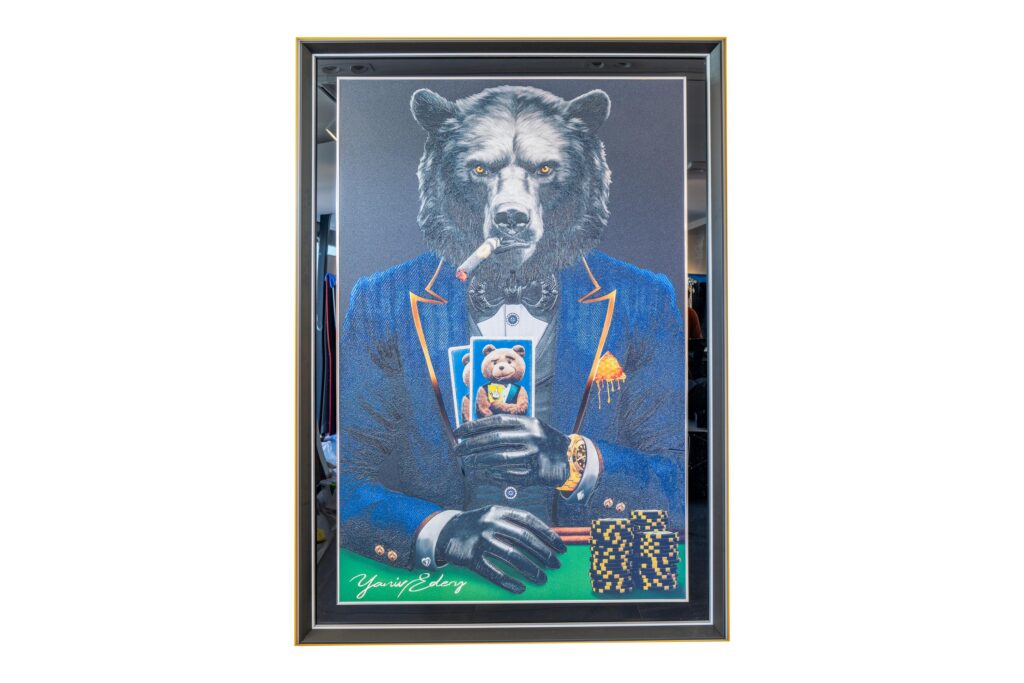 Yaniv Edery – Bear Pok’Art Blue Suit is een kunstwerk dat kracht, mystiek en luxe uitstraalt. De trotse beer zit stevig aan de pokertafel, gekleed in een stijlvol blauw pak met verfijnde oranje accenten. Zijn intense blik en strakke houding geven direct een gevoel van controle en vastberadenheid. Dit werk combineert elegantie met de rauwe energie van een roofdier. De beer rookt een sigaar en houdt zijn kaarten dicht bij zich. Hij straalt zelfvertrouwen en kalmte uit, precies zoals een winnaar zich gedraagt. De chips en gouden details versterken de sfeer van luxe en macht. Het is een spel van risico en beloning, maar ook van houding en charisma. Het blauwe pak speelt hierin een centrale rol. Blauw staat symbool voor betrouwbaarheid, kracht en wijsheid. Door dit te combineren met de onverschrokken beer ontstaat er een unieke harmonie tussen stijl en natuurkracht. Elk detail, van de textuur van de vacht tot de scherpe lijnen van het pak, is zorgvuldig uitgewerkt. Dit kunstwerk vertelt meer dan alleen een verhaal over poker. Het gaat over strategie, kracht en de kunst om emoties te beheersen. Net zoals in poker is in het leven balans tussen lef en bedachtzaamheid essentieel. De beer belichaamt precies dat: een meester van kracht en kalmte. Bear Pok’Art Blue Suit is niet zomaar een kunstwerk. Het is een statement. Een krachtige toevoeging aan elke ruimte. Een kunstwerk dat blijft boeien, uitdagen en inspireren.