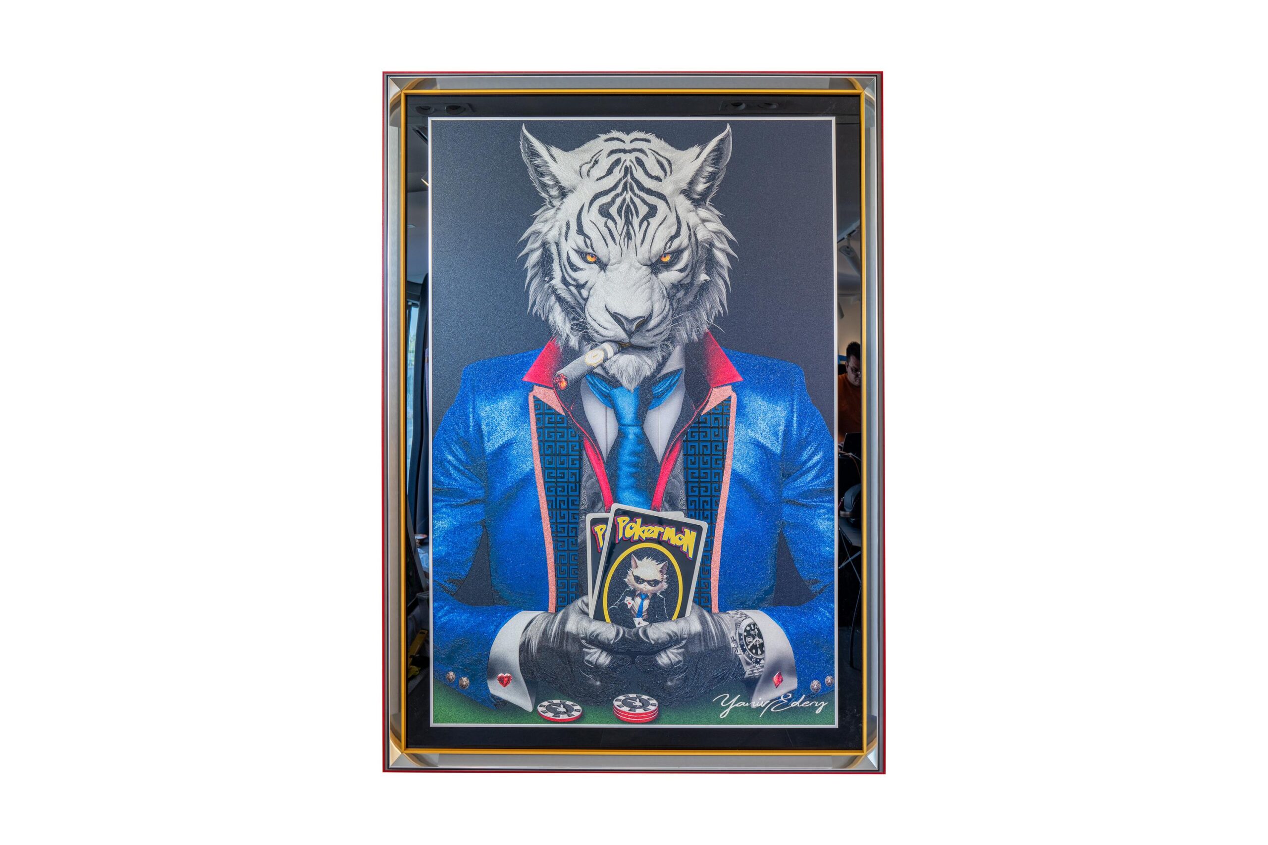 Yaniv Edery – Tiger Pok’Art Blue Suit Medium is een krachtig en intrigerend kunstwerk. Het toont een tijgerfiguur, stijlvol gekleed in een blauw pak, die met zelfverzekerde blik aan de pokertafel zit. De sigaar tussen de tanden en de kaarten in de hand versterken zijn dominante uitstraling. Dit werk ademt kracht, spanning en prestige. Het combineert speelse ironie met een luxueuze uitstraling, waardoor het onmiddellijk de aandacht trekt. De strakke lijnen, felle kleuren en scherpe contrasten maken dit kunstwerk een echte eyecatcher. De tijger symboliseert macht, moed en strategie, terwijl de pokerwereld staat voor risico, lef en succes. Samen creëren ze een verrassende visuele dialoog die blijft intrigeren. Dit werk is niet alleen een schilderij, het is een statement. Ideaal voor wie zijn interieur een iconische en eigentijdse uitstraling wil geven.