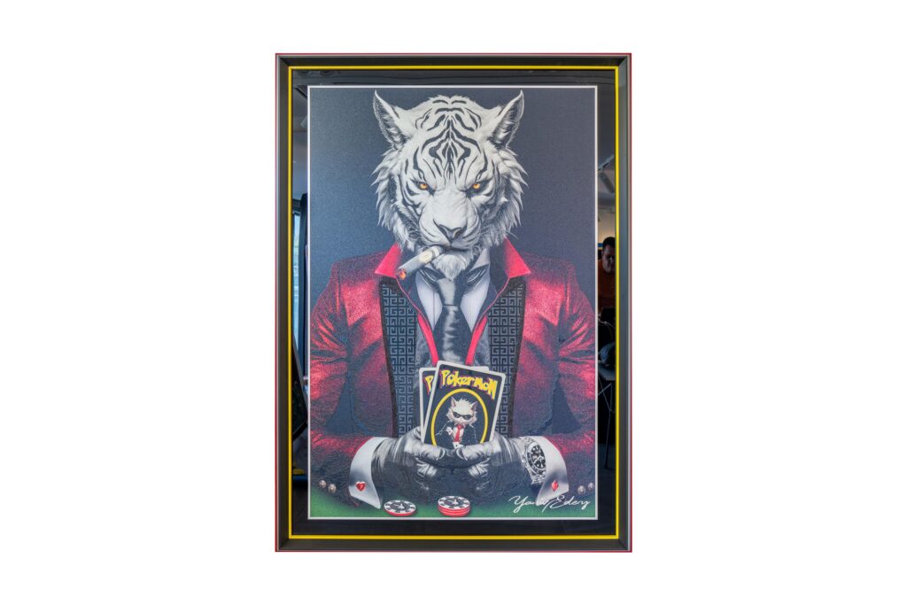 Yaniv Edery – Tiger Pok’Art Red is een werk dat kracht, lef, emotie en luxe samenbrengt. De witte tijger in een felrood pak straalt macht, luxe en charisma uit. Zijn intense blik, de sigaar in zijn mond en de pokerkaarten in zijn handen symboliseren strategie, risico en spel. Dit kunstwerk laat zien hoe elegantie en rauwe kracht elkaar ontmoeten. Het rood van het pak is opvallend en niet toevallig gekozen. Rood staat voor passie, energie en vastberadenheid. Daardoor trekt het kunstwerk direct de aandacht. Bovendien geeft het de tijger een haast vorstelijke uitstraling. Elk detail is zorgvuldig aangebracht: van de textuur van het pak tot de realistische weergave van de tijgerkop. Dit maakt het werk zowel decoratief als betekenisvol. Plaats dit kunstwerk in een ruimte en de sfeer verandert meteen. Het werk domineert en inspireert tegelijk. Het nodigt uit tot gesprek en zet aan tot reflectie. Het combineert dierlijke kracht met de symboliek van poker: keuzes, strategie en durf. Daardoor is het niet alleen een visuele blikvanger, maar ook een statement over lef en macht.