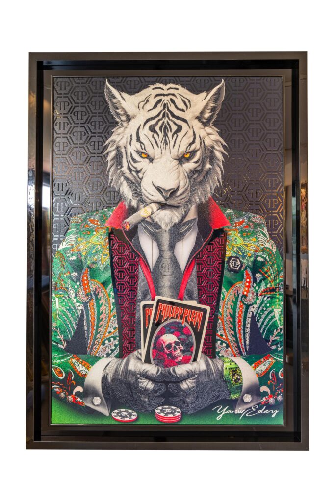 Yaniv Edery – Tiger Poker Philipp Plein Black and Green is een kunstwerk dat kracht, luxe en stijl perfect samenbrengt. De witte tijger, met zijn intense blik en sigaar, zit statig achter een pokertafel. Hij houdt de winnende kaarten stevig vast. De gedetailleerde uitwerking van de Philipp Plein-jas in zwart en groen maakt het werk extra opvallend. Dit is niet zomaar een schilderij. Het is een symbool van macht, lef en verfijning. De tijger in dit werk straalt strategie en dominantie uit. Zijn aanwezigheid dwingt respect af. De combinatie van pokerkaarten, fiches en het luxueuze design van de jas versterkt het verhaal. Het is kunst die verder gaat dan decoratie. Het vertelt iets over overwinning, keuzes en zelfvertrouwen. De zwarte en groene patronen geven diepte en energie aan het geheel. Daardoor krijgt de tijger een nog sterkere uitstraling. Elk detail, van de patronen op de jas tot de rook van de sigaar, laat zien hoe precies en creatief Yaniv Edery werkt. Het kunstwerk is daarmee een echte eyecatcher. Plaats dit werk in een moderne ruimte en de sfeer verandert direct. Het brengt spanning, kracht en luxe samen in één beeld. Dit is kunst die indruk maakt, uitnodigt en blijft fascineren.