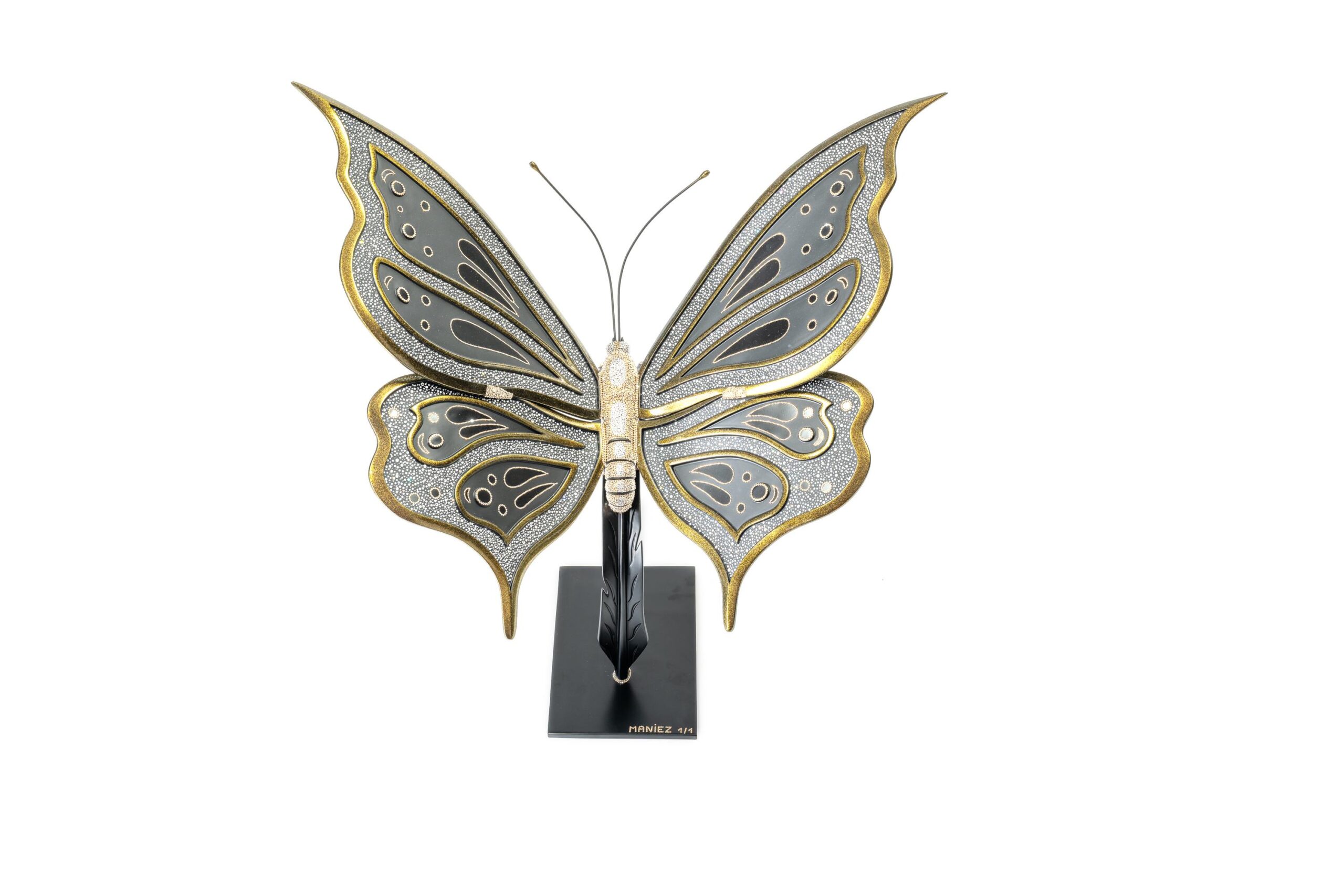 Butterfly Black and Gold – Eddy Maniez Butterfly Black and Gold van Eddy Maniez is een adembenemend kunstwerk waarin elegantie, luxe en symboliek samenkomen. Deze sculptuur toont een sierlijke vlinder, uitgevoerd in diepe zwarte tinten en rijk afgewerkt met gouden accenten. De vleugels zijn ingelegd met talloze fonkelende Swarovski kristallen, waardoor het werk schittert zodra het licht erop valt. Het contrast tussen het donkere zwart en het warme goud benadrukt de gracieuze vormen en geeft de vlinder een bijna koninklijke uitstraling. Bovendien is de vlinder al eeuwenlang een krachtig symbool voor transformatie, vrijheid en schoonheid. In Butterfly Black and Gold verheft Maniez dit symbool tot een luxueus icoon. De perfecte balans tussen verfijnde details en sprankelende weelde maakt het kunstwerk zowel modern als tijdloos. De sculptuur is niet alleen een ode aan de natuur, maar ook een expressie van elegantie en kracht. Dit kunstwerk trekt onmiddellijk de aandacht. De ranke vormen, rijke materialen en schitterende details zorgen ervoor dat het een echte eyecatcher is in iedere ruimte. Butterfly Black and Gold is meer dan decoratie; het is een statement piece dat verfijning en luxe belichaamt.