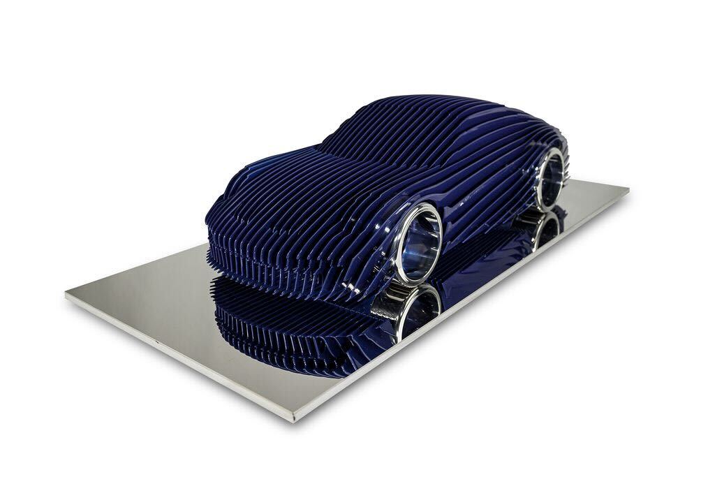 Antoine Dufilho – Porsche GT3 Touring -  Blue De Porsche GT3 Touring - Blue van Antoine Dufilho is een meesterwerk van moderne sculptuur. Het werk vangt de essentie van snelheid, elegantie en perfectie in één vloeiende vorm. Gemaakt van zorgvuldig gevormde metalen lagen, lijkt de auto te bewegen – zelfs in stilstand. De strakke lijnen en de diepblauwe kleur zorgen voor een krachtige visuele impact. Bovendien weerspiegelt het gepolijste oppervlak het licht, waardoor het kunstwerk een dynamisch karakter krijgt. Dufilho speelt met ritme en transparantie, en laat de toeschouwer de balans tussen techniek en kunst ervaren. Elke curve, elke opening en elke schaduw vertelt een verhaal van vakmanschap. De Porsche GT3 Touring -  Blue symboliseert de perfecte harmonie tussen mens, machine en design. Daarom is het niet zomaar een sculptuur, maar een ode aan innovatie en snelheid. De naam “Touring Blue” verwijst subtiel naar de eeuwige verbinding tussen passie en precisie – net als een ring die nooit zijn glans verliest. Dit werk combineert esthetiek, emotie en techniek op een unieke manier die typisch is voor Dufilho.